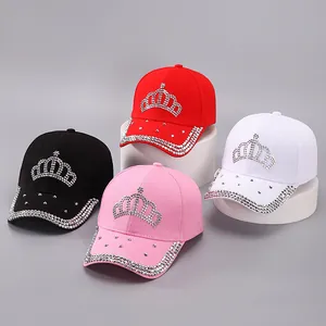 Détail de casquettes de baseball avec motifs couronne en strass noir, rouge, rose et blanc