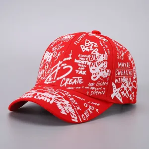Close-up of red baseball cap with white street-style graffiti letters and ribbon details