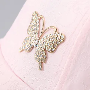 Macro shot of sparkling rhinestone butterfly detail on a pink textured baseball cap