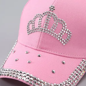 Détail de casquette en coton rose avec des motifs de couronnes en strass argentés