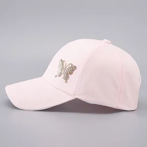 Detailed view of pink baseball cap featuring jacquard fabric and rhinestone butterfly ornament