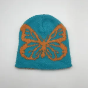 Dettaglio del berretto jacquard morbido con motivo a farfalla arancione su blu intenso