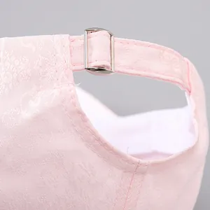 Detail of light pink baseball cap with floral jacquard texture and silver metal buckle
