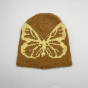 Dettaglio della texture in peluche del berretto marrone con motivo jacquard a farfalla gialla