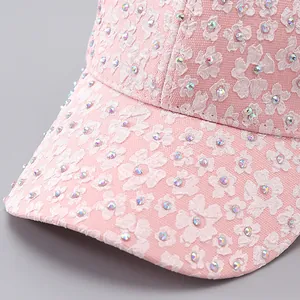 Detailed view of pink floral lace fabric and shimmering rhinestones on the baseball cap