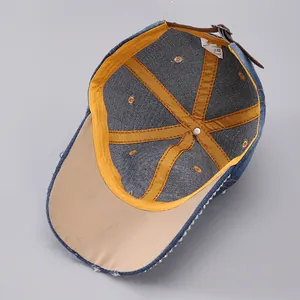 Detailed interior of denim baseball cap with yellow seam tape and rhinestone brim edge