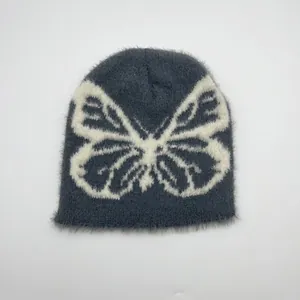Vista dettagliata del berretto in morbido peluche grigio con motivo jacquard a farfalla bianca