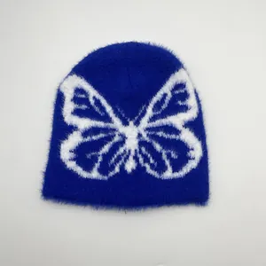 Dettaglio del berretto in peluche blu con motivo jacquard a farfalla bianca e trama morbida