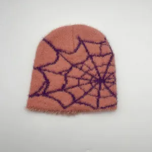 Détail du bonnet en maille rose pelucheux avec motif toile d'araignée violette et texture