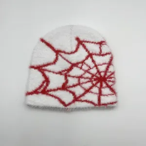 Détail d'un bonnet en fausse fourrure blanche avec motif jacquard de toile d'araignée rouge