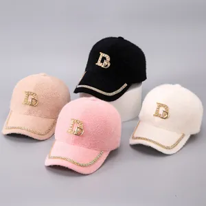 Detail von vier Plüsch-Basecaps aus Nerzsamt mit glänzenden Strass-D-Logos in Pastell