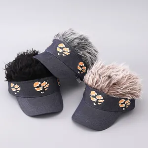 Drei Visier-Mützen mit Perücken in Schwarz, Grau und Braun auf blauem Denim-Stoff