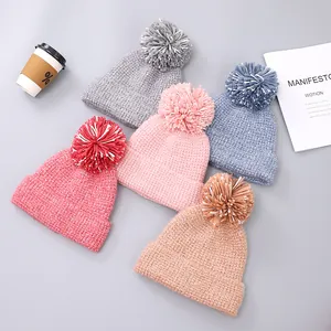 Detail of thick cable knit winter hats with large two-tone pom-poms in five assorted colors