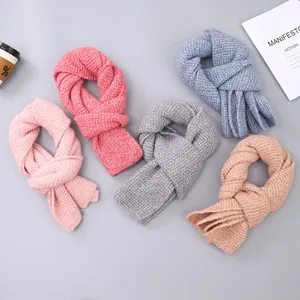 Flat lay of colorful waffle knit scarves in pink, grey and blue with tassel details