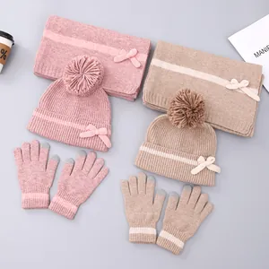 Detailopname van gebreide winterset met pompon muts, sjaal en touchscreen handschoenen