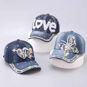 Detail of denim baseball caps with rhinestones in LOVE, butterfly, and heart designs