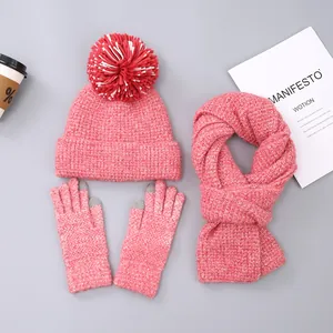 Detailed flat lay of pink winter knit set with pompom hat, scarf, and touchscreen gloves
