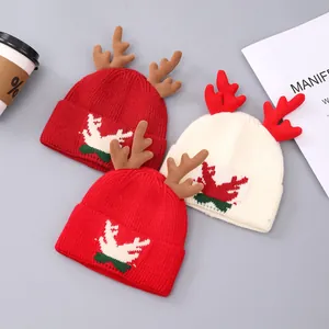 Detailopname van rode en crèmekleurige gebreide kerstmutsen met zachte rendiergeweien