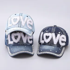 Detail of denim baseball hat with pearl LOVE patch and rhinestone trim on the brim