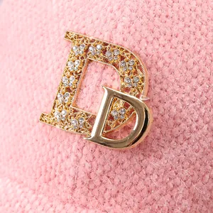 Makroaufnahme der rosa Pelz-Basecap mit kristallbesetztem Metall-D-Buchstaben für Damen