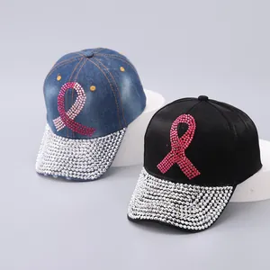 Detail of baseball caps with pink rhinestone ribbon and sparkling brim on denim and satin