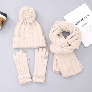 Flat lay of cream knit winter set featuring bobble hat, scarf and touchscreen gloves