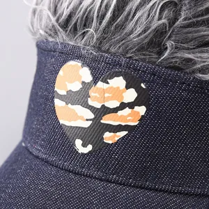 Makroansicht der Denim-Visierkappe mit Herzaufdruck und flauschigem grauem Kunsthaar