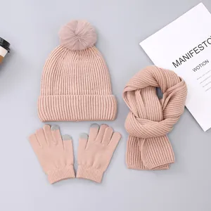 Detail of pink knitted winter set with pompom hat, scarf and touchscreen gloves