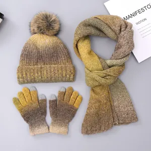 Detailed view of yellow tie-dye knit hat, scarf, and touchscreen gloves with faux fur pom