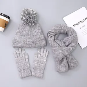 Close-up of winter knit set including touchscreen gloves, scarf, and pompom beanie