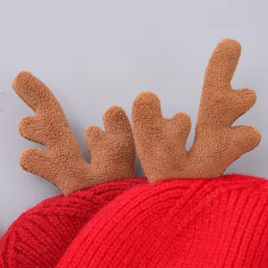 Detailopname van rode gebreide kerstmuts met zachte pluche rendiergewei versieringen
