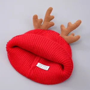 Detail van rode kerstmuts met gewei en materiaallabel van 100% acryl voor de winter
