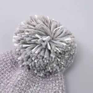 Close-up of winter knit hat with a mixed grey and white fluffy faux fur pompom detail