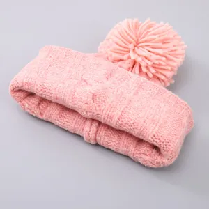 Detail of pink cable knit beanie with a fluffy oversized pom-pom for winter warmth