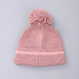Detail van een roze gebreide muts met pompon en gestreepte rand voor de koude winter