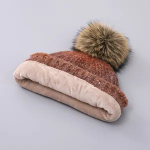 Detail of warm cable knit beanie with faux fur pompom and cozy thick fleece lining