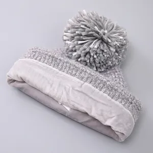 Detail of gray cable-knit winter hat with fuzzy pompom and soft fleece inner lining