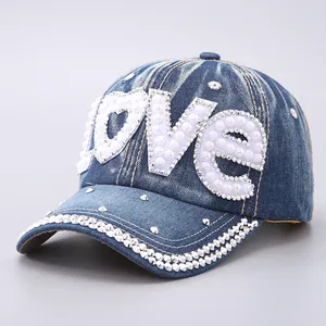 Detailed view of the sparkling rhinestone Love lettering and pearls on a blue denim cap