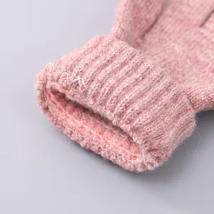 Detail van roze gebreide handschoen met dikke geribbelde manchet en warme textuur