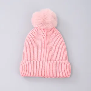Close-up of chunky knit texture and soft faux fur pom-pom on the pink beanie