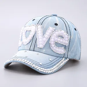 Detailed close-up of denim baseball cap with LOVE rhinestone and pearl embroidery