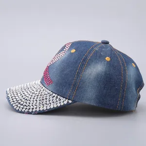 Detailed view of rhinestone-studded brim and gradient pink crystal letters on denim cap