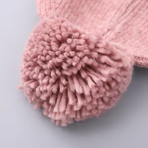 Detailopname van de roze geribbelde gebreide muts met een grote pluizige pompon-versiering