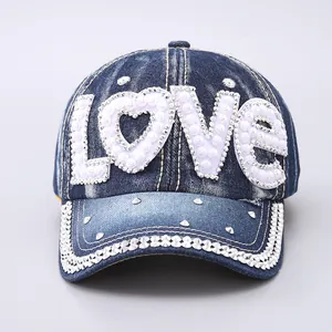 Detailed close-up of the Love letters with pearls and crystals on the denim baseball cap