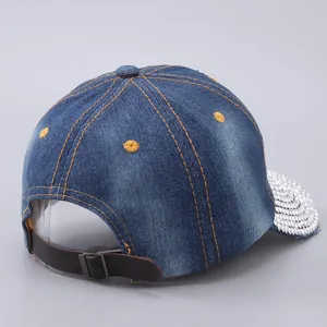 Detail of blue denim baseball cap featuring sparkling rhinestones on the brim and leather strap