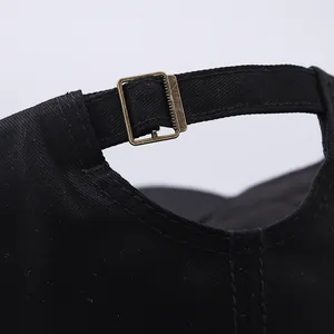 Close-up of adjustable metal buckle and stitching on black washed cotton baseball cap