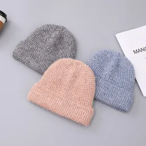 Detailed knit texture of three warm winter beanies in grey, pink and light blue colors
