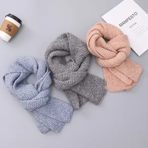 Detailed view of thick knit winter scarves in blue, dark grey, and dusty pink soft textures
