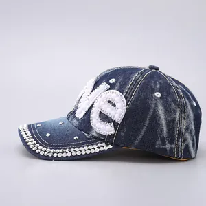 Detailed macro of denim baseball cap featuring pearl LOVE letters and rhinestone brim