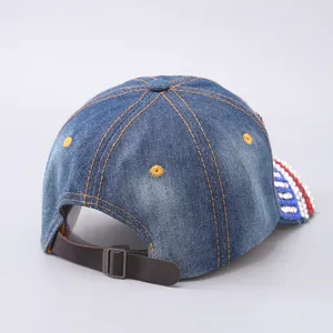 Dettaglio cappello baseball in denim blu con strass scintillanti e cinturino in pelle